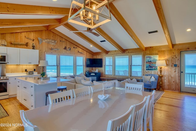 dining area with a wealth of natural light, lofted ceiling with beams, and light wood-type flooring