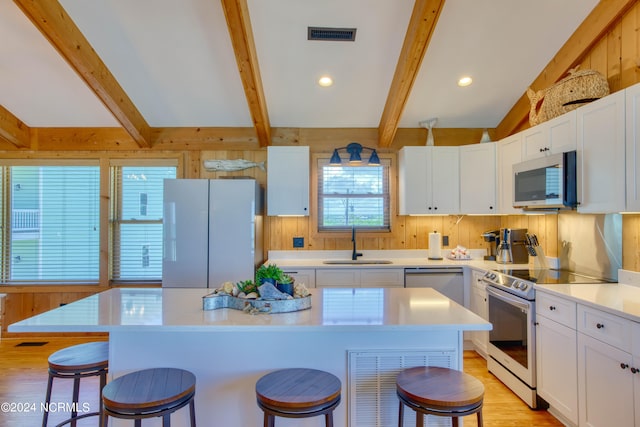 kitchen featuring sink, a center island, beamed ceiling, and appliances with stainless steel finishes