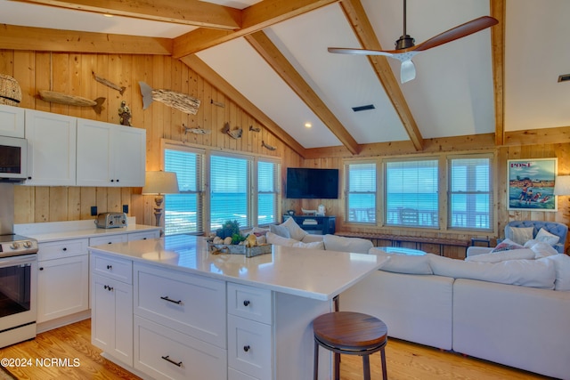 kitchen with a kitchen island, vaulted ceiling with beams, white appliances, a kitchen bar, and white cabinets