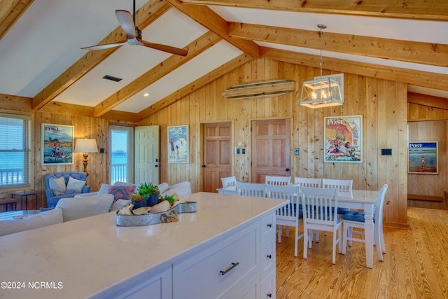 kitchen with vaulted ceiling with beams, white cabinetry, light hardwood / wood-style flooring, and hanging light fixtures