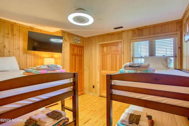 bedroom with wooden walls and light hardwood / wood-style floors