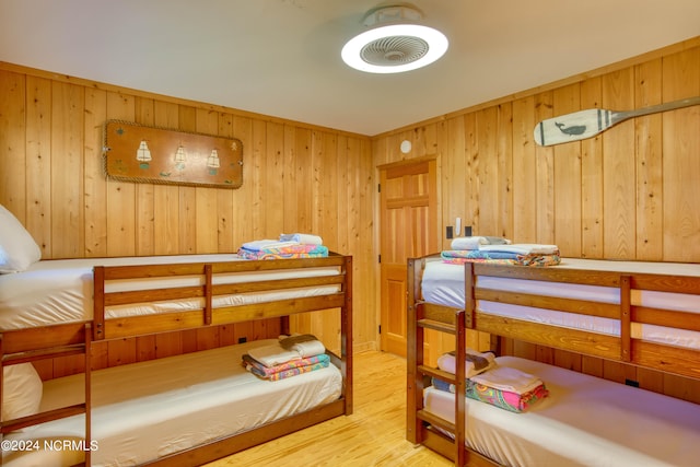 bedroom with wooden walls and wood-type flooring