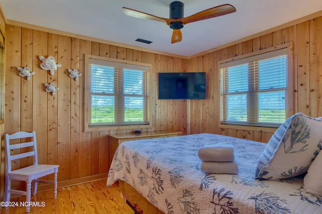 bedroom with light hardwood / wood-style floors, multiple windows, ornamental molding, and ceiling fan