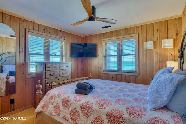 bedroom with wood-type flooring, ceiling fan, and wooden walls