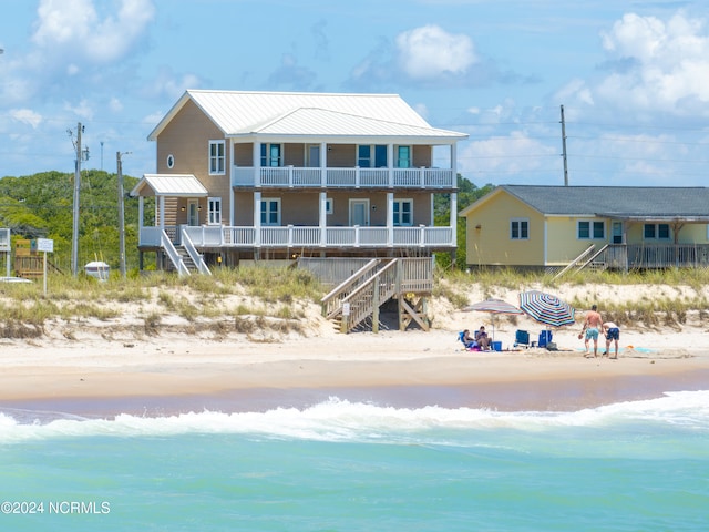 rear view of property featuring a balcony and a view of the beach