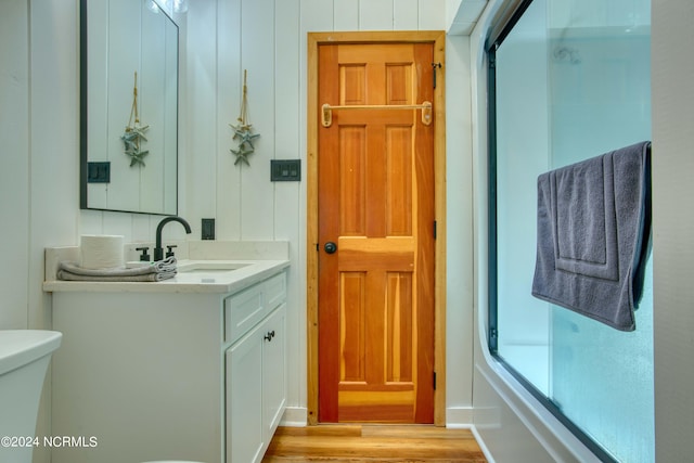 full bathroom featuring hardwood / wood-style floors, vanity, bath / shower combo with glass door, and toilet