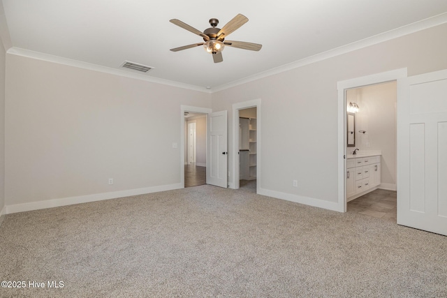 unfurnished bedroom with connected bathroom, a walk in closet, ceiling fan, and light colored carpet