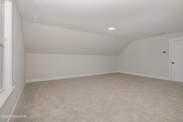 additional living space with light colored carpet and vaulted ceiling