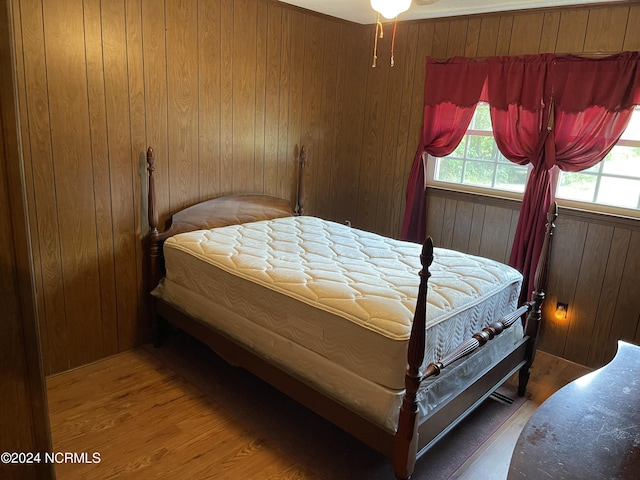 bedroom featuring wooden walls and wood finished floors