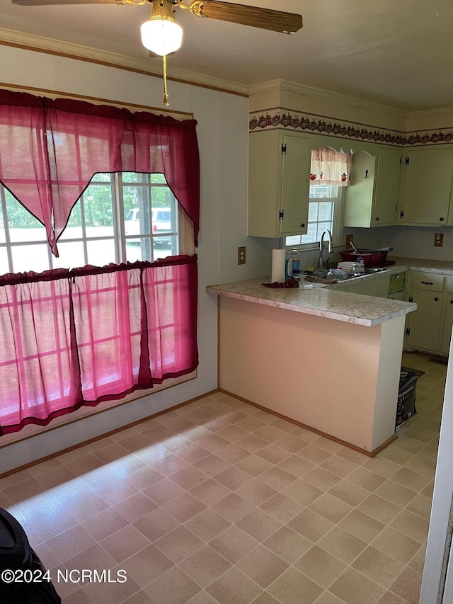 kitchen featuring a peninsula, a sink, green cabinets, light countertops, and ornamental molding