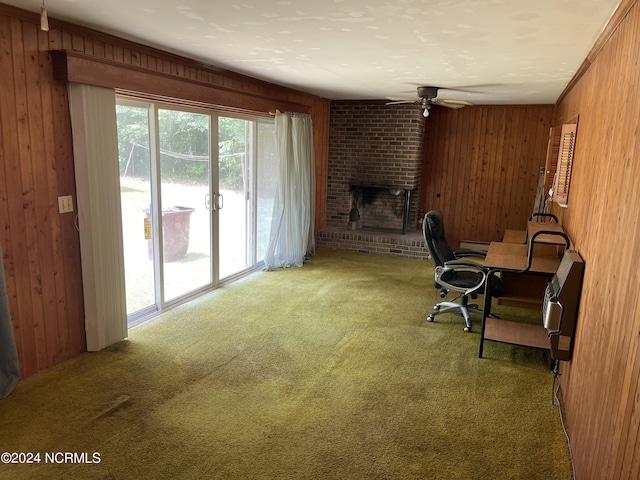 home office with a ceiling fan, carpet, wood walls, a fireplace, and a baseboard heating unit