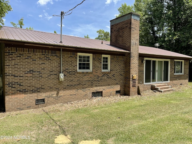 rear view of house with entry steps, a chimney, metal roof, crawl space, and brick siding