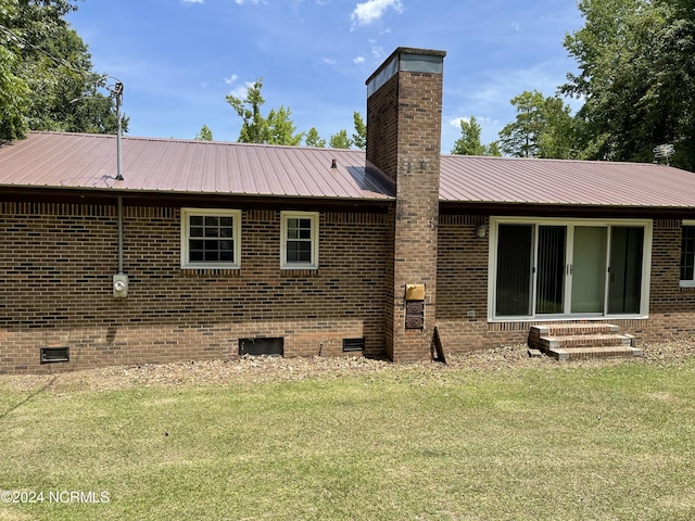 rear view of property featuring crawl space, a yard, a chimney, and brick siding