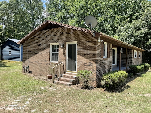 view of front of home with entry steps, brick siding, and a front yard