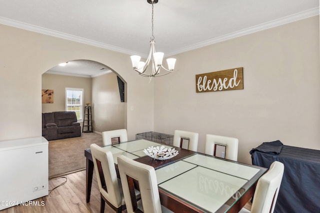 dining space with a notable chandelier, ornamental molding, and light hardwood / wood-style floors