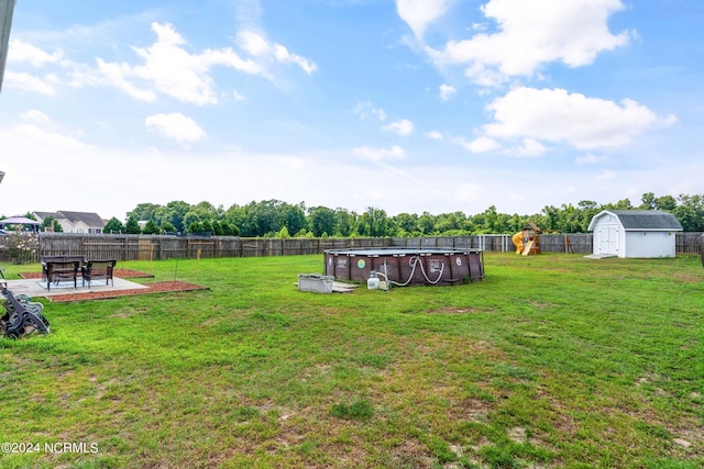 view of yard with a fenced in pool, a storage unit, and a patio