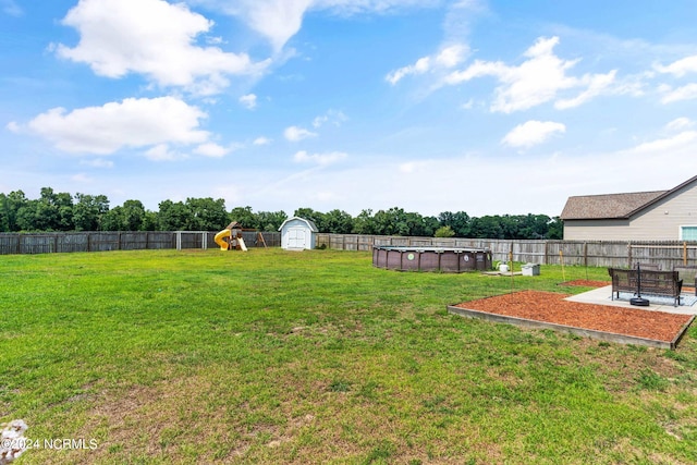 view of yard with a playground, a fenced in pool, and a storage unit