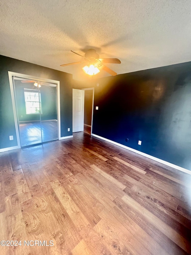 unfurnished bedroom featuring hardwood / wood-style flooring, a closet, ceiling fan, and a textured ceiling