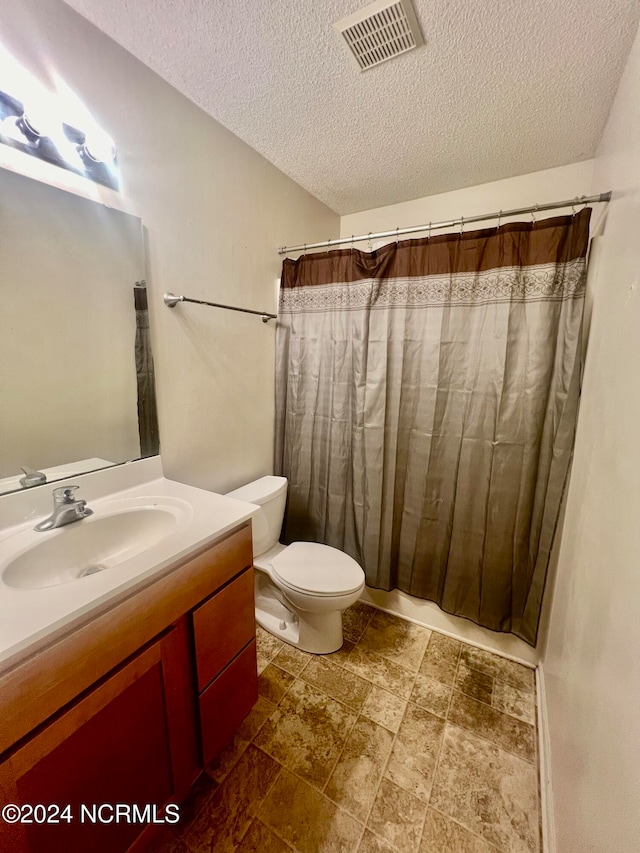 bathroom with toilet, a textured ceiling, and vanity