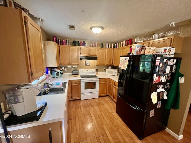 kitchen featuring white appliances, light wood-type flooring, sink, and a textured ceiling