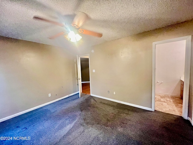 interior space with a textured ceiling, dark colored carpet, and ceiling fan