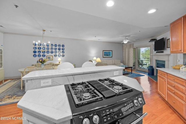 kitchen featuring light wood-type flooring, ceiling fan with notable chandelier, black / electric stove, a kitchen island, and ornamental molding