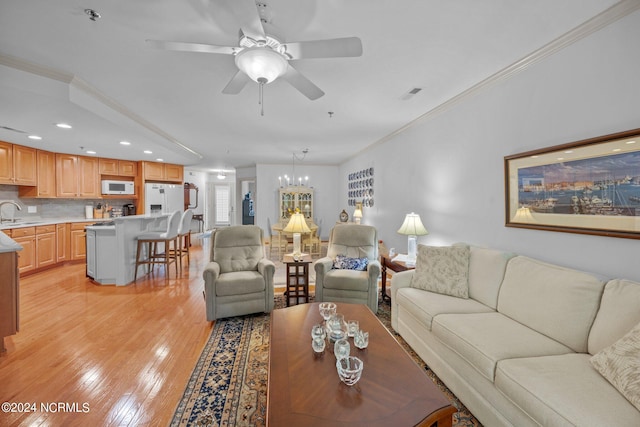 living room featuring sink, ornamental molding, ceiling fan with notable chandelier, and light hardwood / wood-style floors