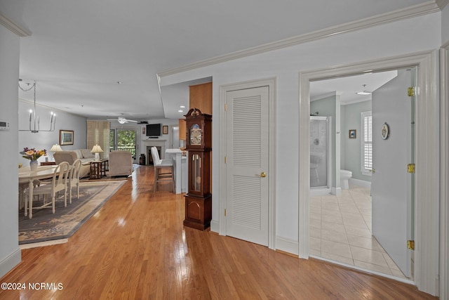 hallway featuring ornamental molding, light hardwood / wood-style flooring, and a notable chandelier