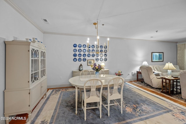 dining space featuring hardwood / wood-style floors, a chandelier, and crown molding