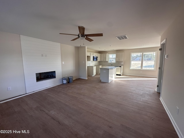 unfurnished living room with ceiling fan, wood-type flooring, and a fireplace