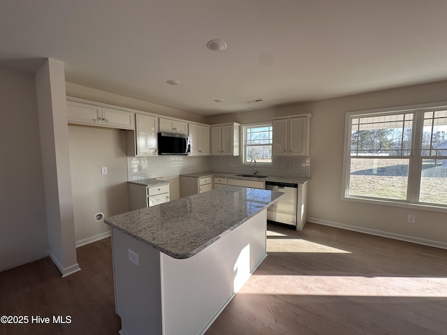 kitchen with backsplash, a center island, white cabinetry, light stone countertops, and appliances with stainless steel finishes