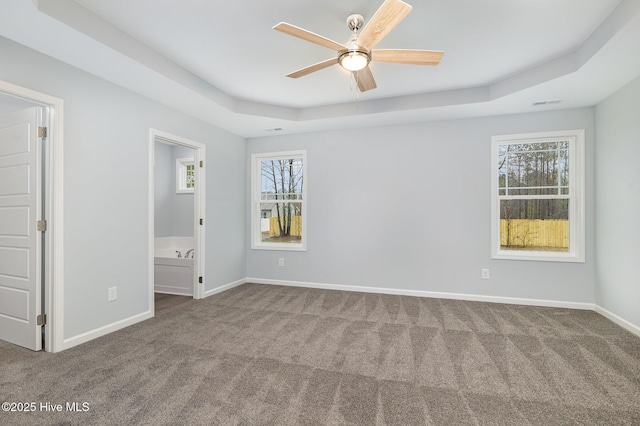 unfurnished bedroom with connected bathroom, a tray ceiling, ceiling fan, and carpet