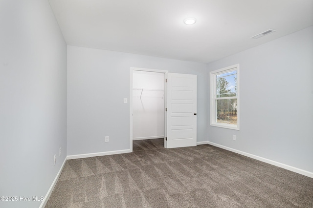 unfurnished bedroom with a walk in closet, carpet floors, and a closet