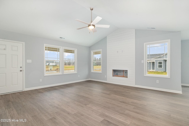 unfurnished living room with a healthy amount of sunlight, a large fireplace, and light hardwood / wood-style flooring