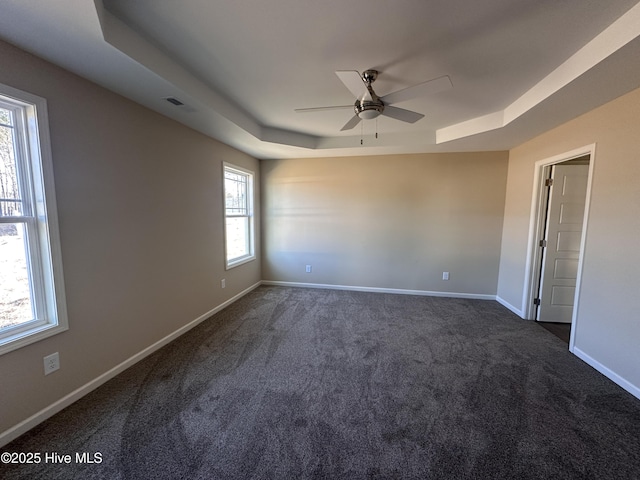 carpeted spare room with ceiling fan and a raised ceiling