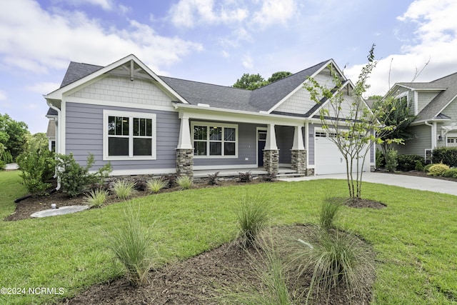 craftsman-style home with a front yard, stone siding, covered porch, and driveway