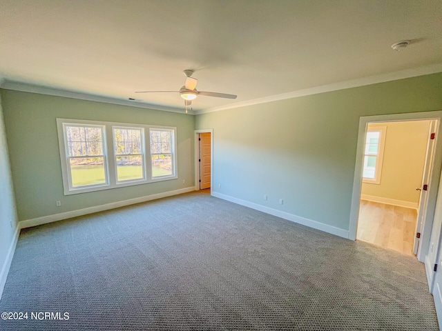 spare room featuring light carpet, ornamental molding, and ceiling fan