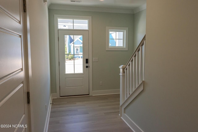 doorway with light wood-type flooring and ornamental molding