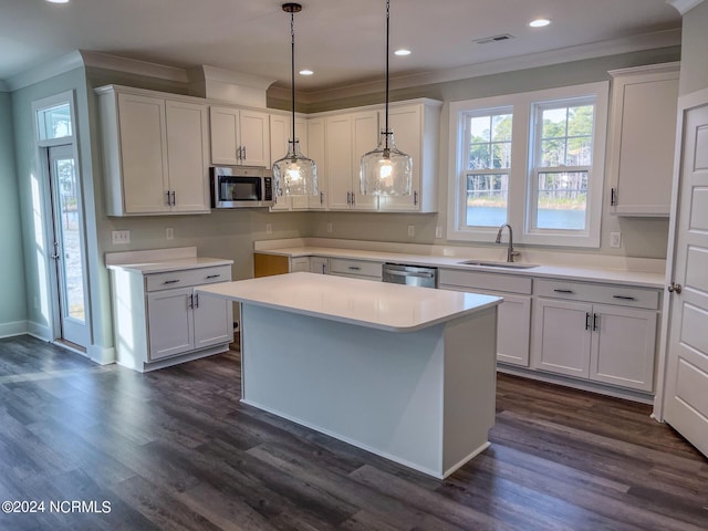 kitchen with stainless steel appliances, sink, decorative light fixtures, white cabinetry, and a center island