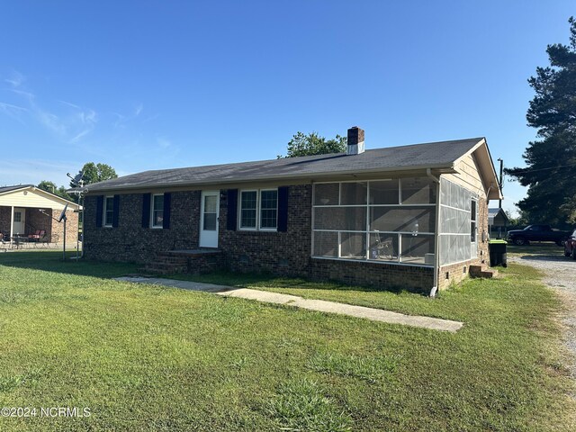 view of front of house with a front lawn and a sunroom