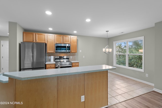 kitchen featuring backsplash, pendant lighting, light wood-type flooring, and appliances with stainless steel finishes