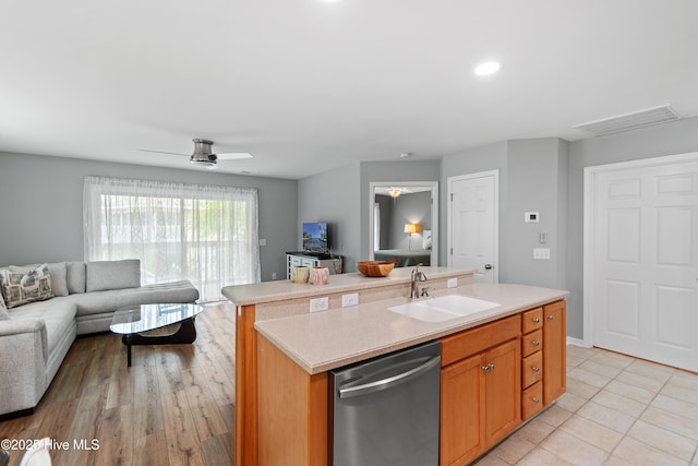kitchen featuring dishwasher, open floor plan, a sink, light countertops, and a kitchen island with sink