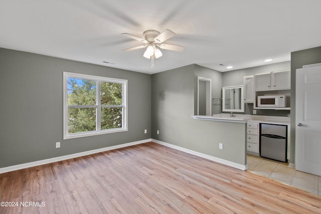 kitchen with gray cabinets, stainless steel fridge, light hardwood / wood-style flooring, and ceiling fan