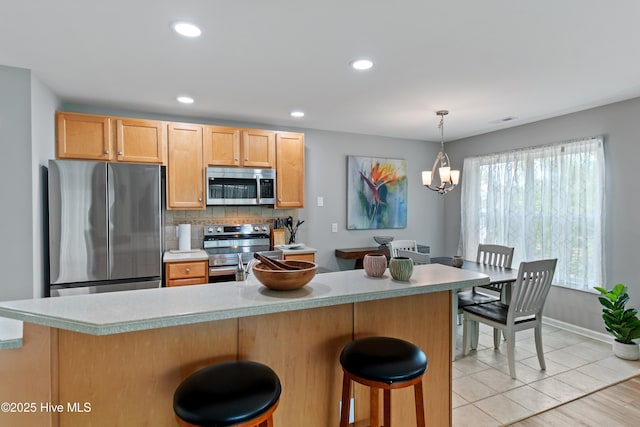kitchen featuring stainless steel appliances, decorative backsplash, a chandelier, light countertops, and recessed lighting
