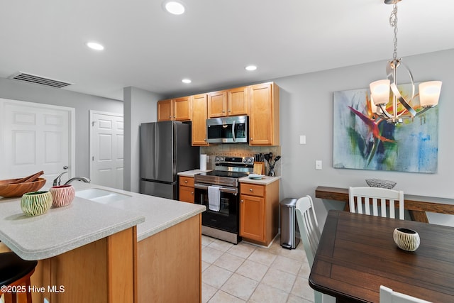 kitchen featuring stainless steel appliances, a sink, light countertops, decorative backsplash, and a chandelier