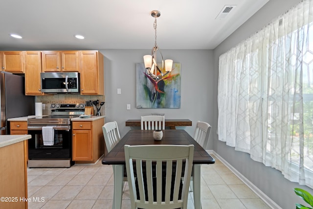kitchen with appliances with stainless steel finishes, light tile patterned flooring, tasteful backsplash, light countertops, and plenty of natural light