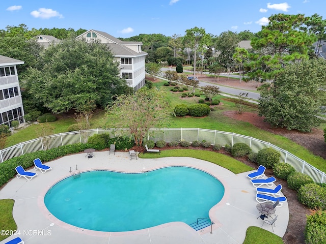 community pool featuring a fenced backyard and view of wooded area