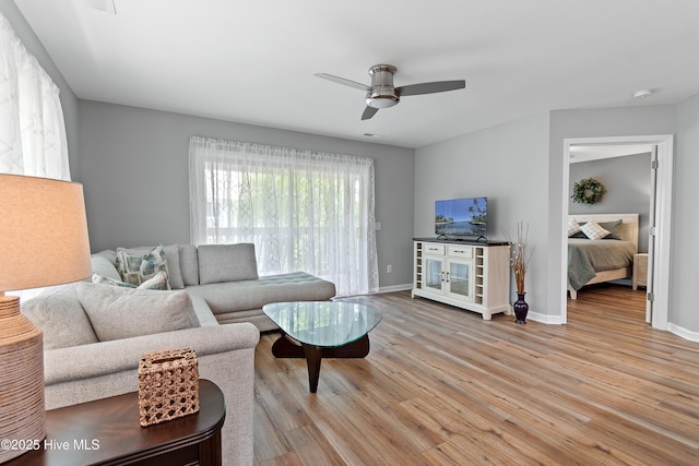 living area with wood finished floors, a ceiling fan, and baseboards