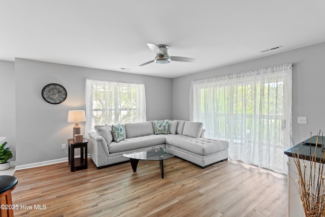 living area with wood finished floors, ceiling fan, healthy amount of natural light, and baseboards