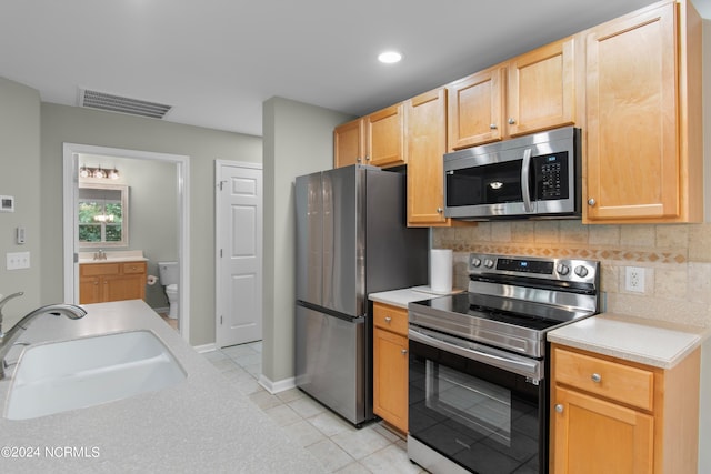 kitchen with decorative backsplash, sink, light tile patterned floors, and stainless steel appliances